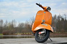 an orange scooter parked on top of a wooden platform