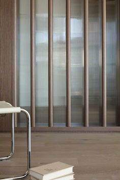 a stack of books sitting on top of a wooden floor next to a white chair