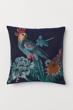 a blue pillow with an image of a bird on it's back and flowers in the background