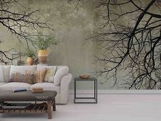 a white couch sitting in front of a wall with trees on it's side