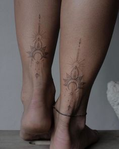 two women's legs with sun and moon tattoos on them