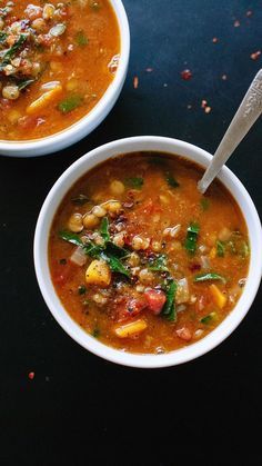 two bowls filled with soup on top of a black table next to another bowl full of soup