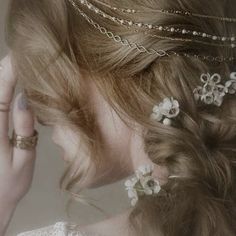 a woman with braids and flowers in her hair is holding her hand up to her ear