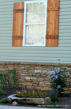 a wooden bench sitting in front of a window on top of a stone block wall