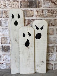 two wooden pieces with black paint on them sitting next to a brick wall in front of a brick wall