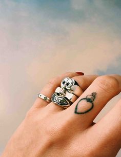 a woman's hand with two rings on it and a skull ring in the middle