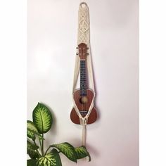 a wooden instrument hanging from the side of a white wall next to a potted plant