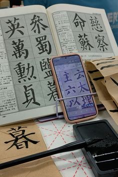 an open book with chinese characters on it and a cell phone sitting in the middle