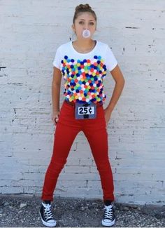 a woman standing in front of a white brick wall with gumballs on her shirt