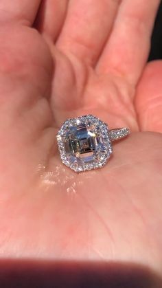 a close up of a person's hand holding an engagement ring