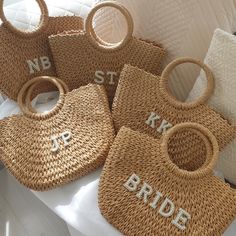 four woven bags with bride and groom names on them sitting on a white bed in front of pillows