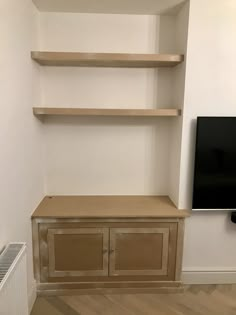 an empty entertainment center with shelves and a flat screen tv mounted on it's wall