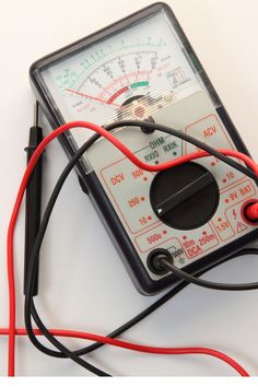 an analog multimeter with red wires connected to it