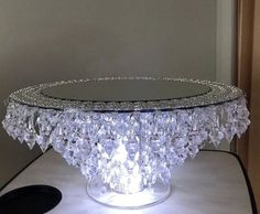 a glass table topped with lots of crystal beads on top of a white table cloth