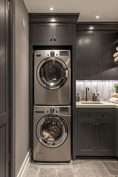 a washer and dryer in a small room with gray cabinets, marble counter tops and flooring