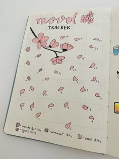 an open notebook with pink flowers and the words travel tracker written in black on it