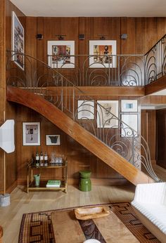 a living room with wood paneling and metal railings on the wall, stairs leading up to the second floor