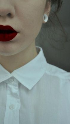 a close up of a woman with red lipstick on her lips and white collared shirt