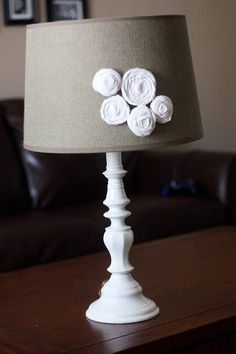 a white lamp with flowers on it sitting on a table in front of a couch