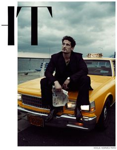 a man sitting on the back of a yellow car in front of an overcast sky