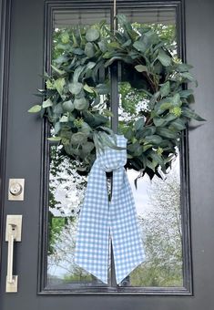 a wreath on the front door with a blue gingham bow hanging from it