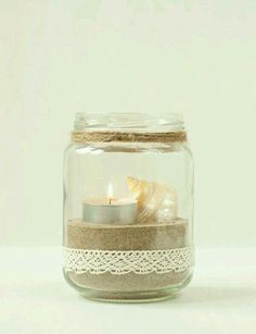 a glass jar filled with sand and a candle