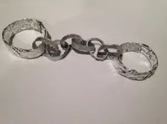 a pair of silver handcuffs on a white surface with one being held by the other