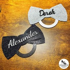 two bow ties with the words dereh and alerander on them sitting on a wooden table