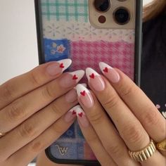 a woman holding up her phone case with hearts on the nails and two gold rings