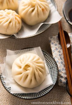 two plates filled with dumplings next to chopsticks on a cloth covered table