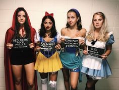 four women dressed in costumes holding up signs