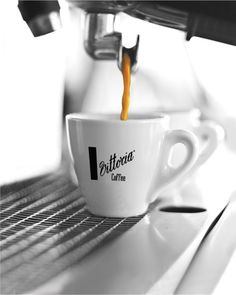 coffee being poured into a cup with the word latteria written on it, in front of an espresso machine