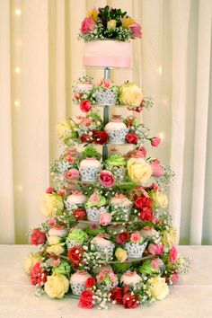 a cake decorated with flowers and cupcakes is on display in front of a curtain