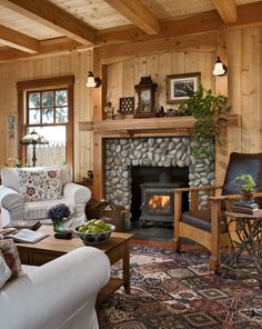 a living room filled with furniture and a fire place in the middle of a wooden wall