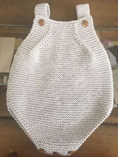 a white knitted bag hanging on a wooden wall next to an open magazine rack