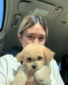 a woman holding a small dog in her lap while sitting in the back seat of a car