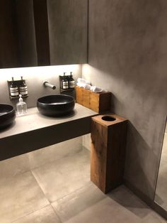 a bathroom with two sinks and mirrors in the corner, one black bowl is on the counter