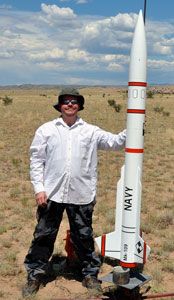 a man standing next to a rocket in the desert