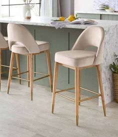 two beige bar stools sitting in front of a marble counter top with lemons on it