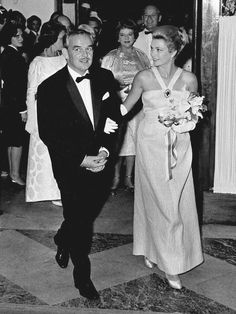 a man in a tuxedo is walking with a woman