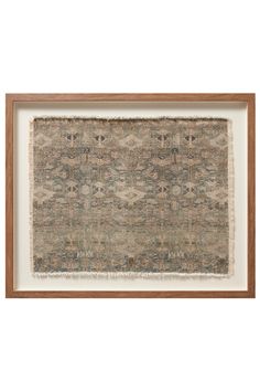 an old rug hanging on the wall in a wooden frame with a white and brown border