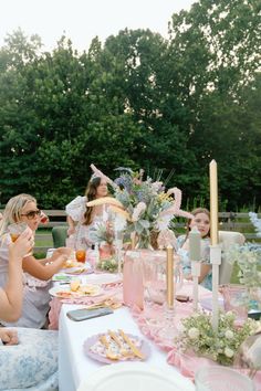 a group of people sitting around a table with food and drinks on top of it