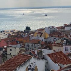 an aerial view of a city with red roofs and the ocean in the back ground