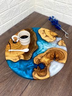 a coffee cup and spoon sitting on top of a wooden tray with blue water in it