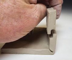 a person is holding a piece of cement with their thumb on the edge of it