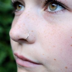 a close up of a person with freckles on their nose and nose ring