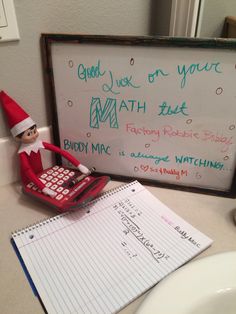 an elf with a calculator and notepad next to a sign