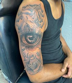 a man with a tattoo on his arm has an eye and roses in the background