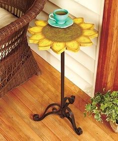 a small table with a cup on it in the middle of a wooden floor next to a wicker chair