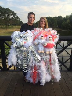 a man and woman standing next to each other on a bridge with some decorations in front of them